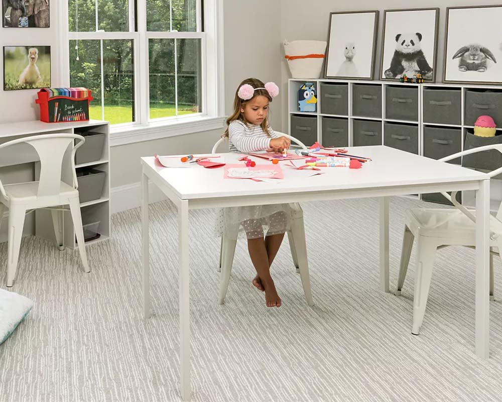 Little girl doing crafts in a white dress on a white carpet