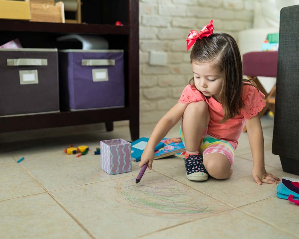 Little girl coloring on tile floor