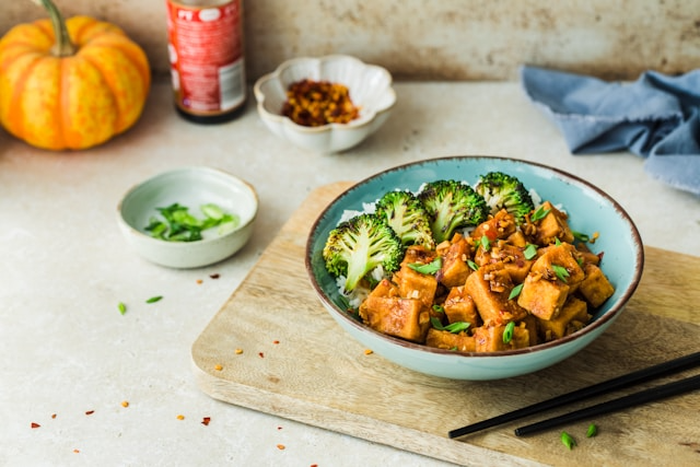 A glass of vegan protein shake surrounded by fresh greens and a measuring tape, symbolizing weight loss.