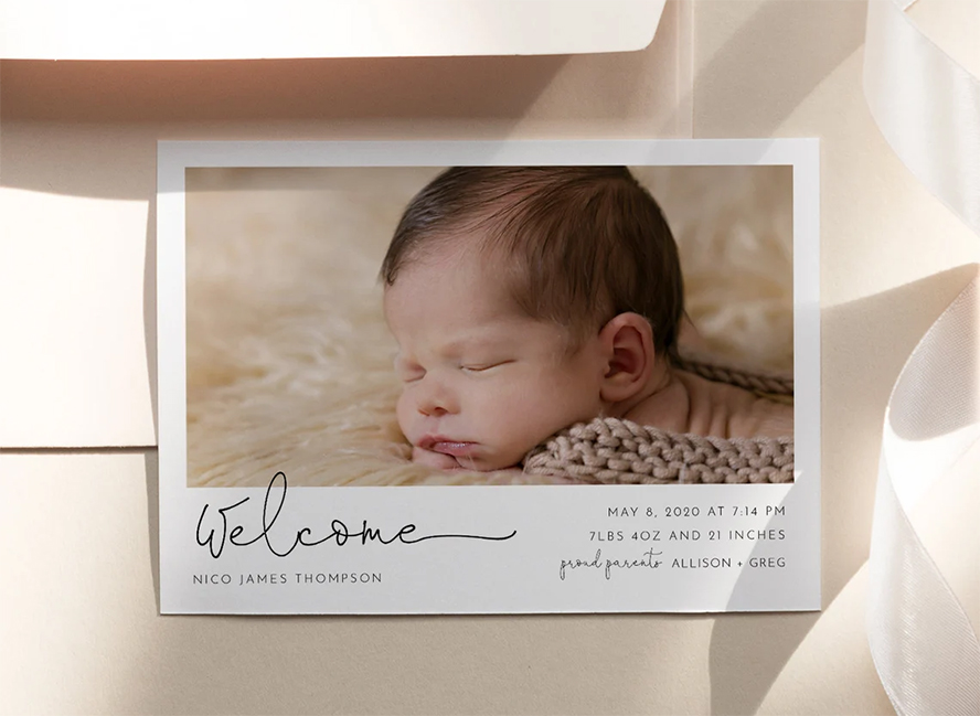 A birth announcement with a baby sleeping in a blanket.